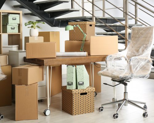 Cardboard boxes and furniture near stairs in office. Moving day